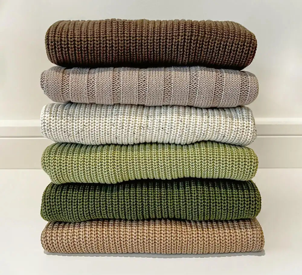 stack of tottles jumpers, neatly folded in a pile, showcasing a variety of mix & match styles and colours