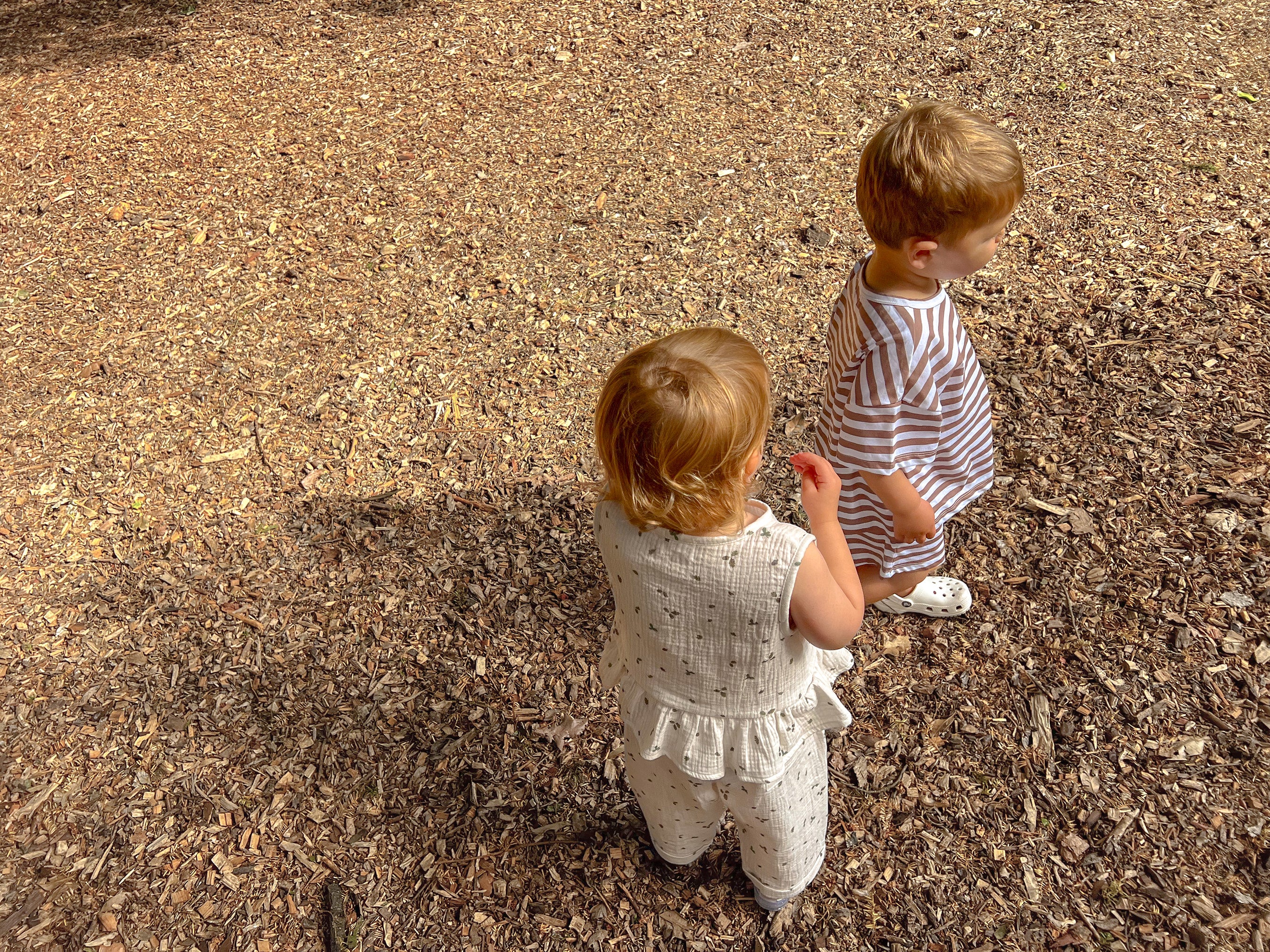 Two children wearing Tottles co-ord outfits standing on a bark surface